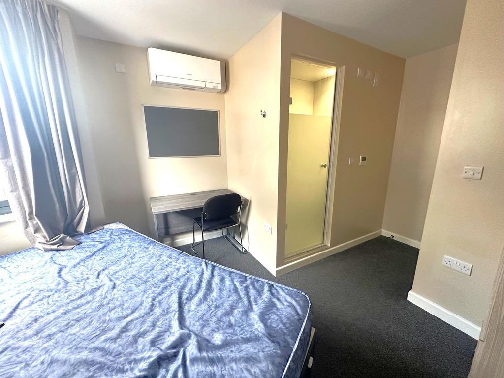 Bright double bedroom with a large window, buil...