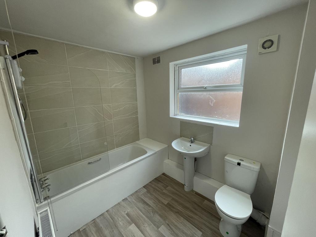 Bright, modern bathroom with a tiled bath/showe...