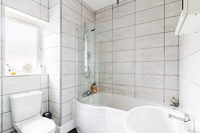Bright, modern bathroom with a curved shower-ba...
