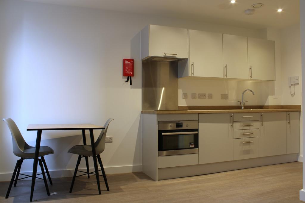 A modern and tidy kitchenette with ample storag...