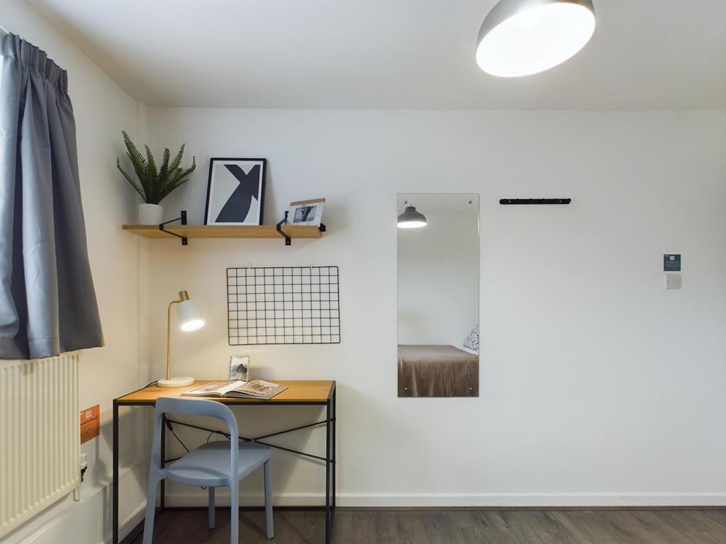 A bright and tidy bedroom featuring a cozy work...