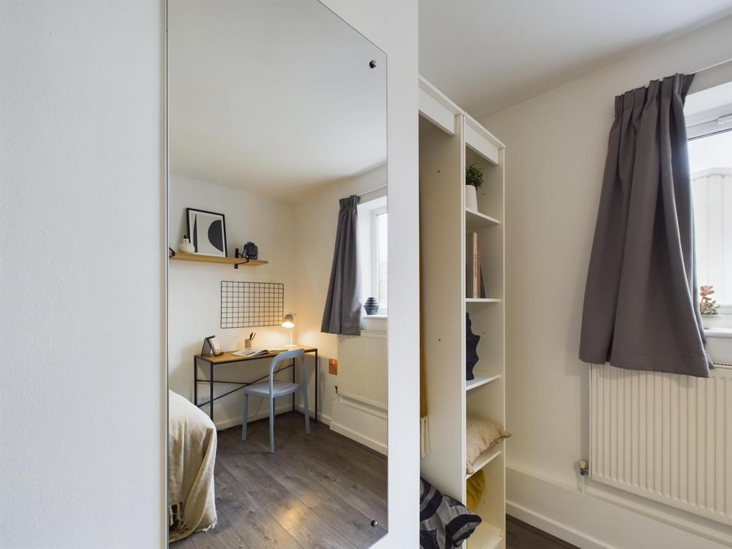 A cozy bedroom featuring a single bed near a wi...