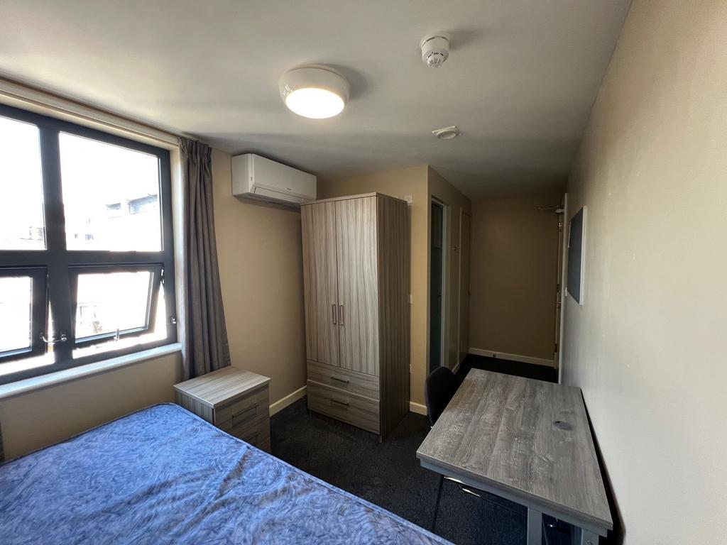 Bright single bedroom with a large window, fitt...