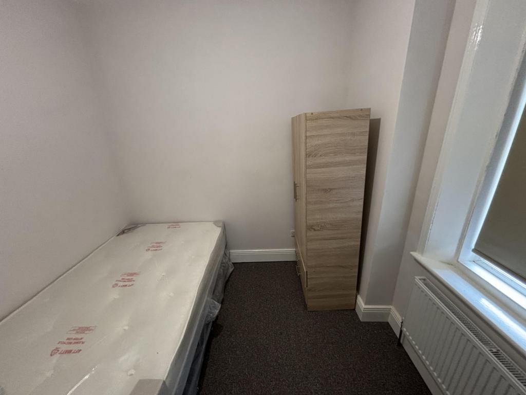 A tidy single bedroom featuring a fitted wardro...