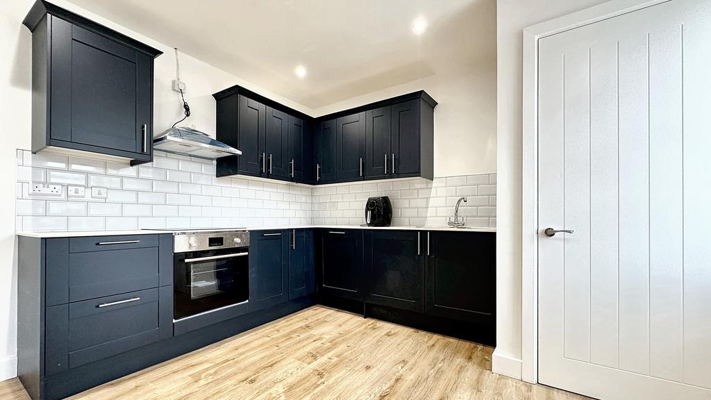 A modern kitchen featuring sleek navy cabinets,...