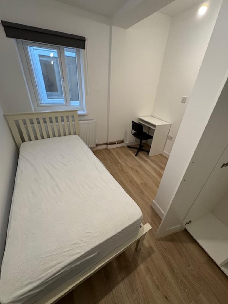 A cozy and well-lit single bedroom featuring a ...