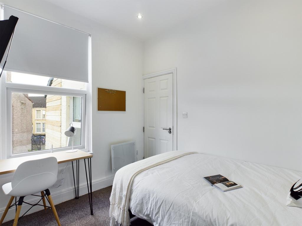 A bright and tidy double bedroom with a cozy de...