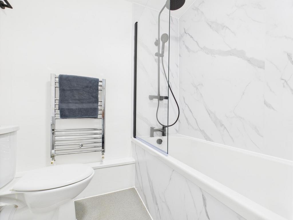 Bright, modern bathroom with a white bath and m...