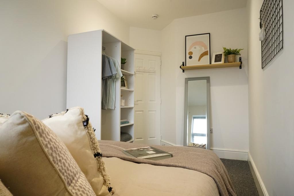A cozy, well-lit bedroom featuring a comfortabl...