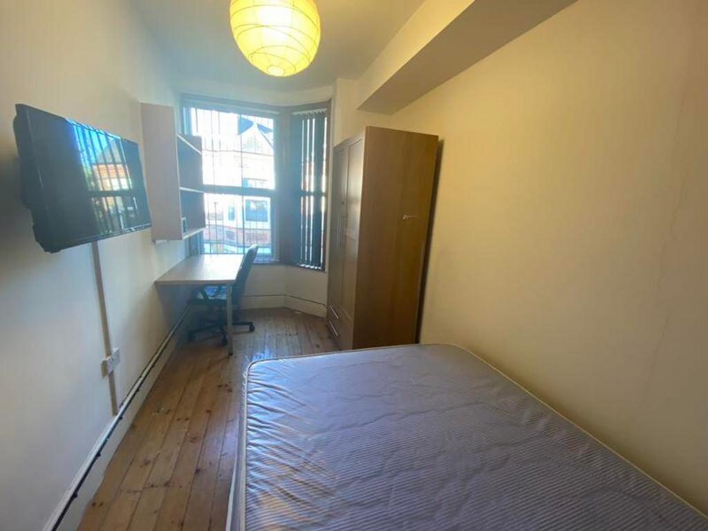 A bright and spacious double bedroom with a des...