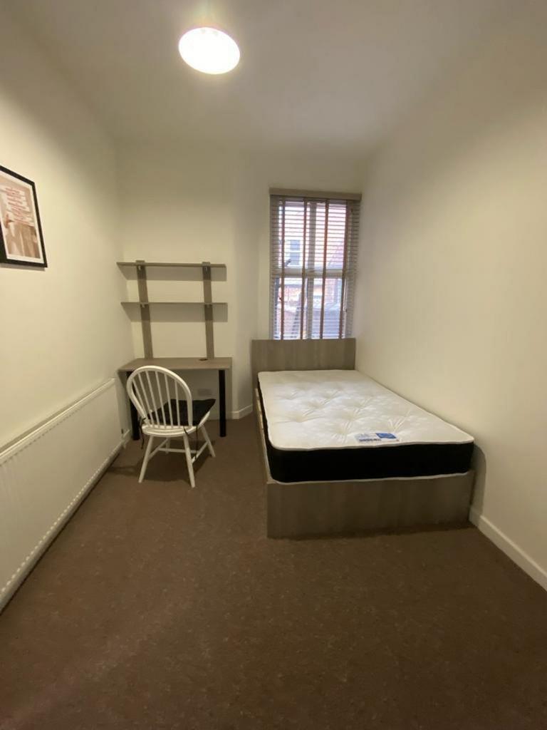 A bright and tidy single bedroom featuring a de...