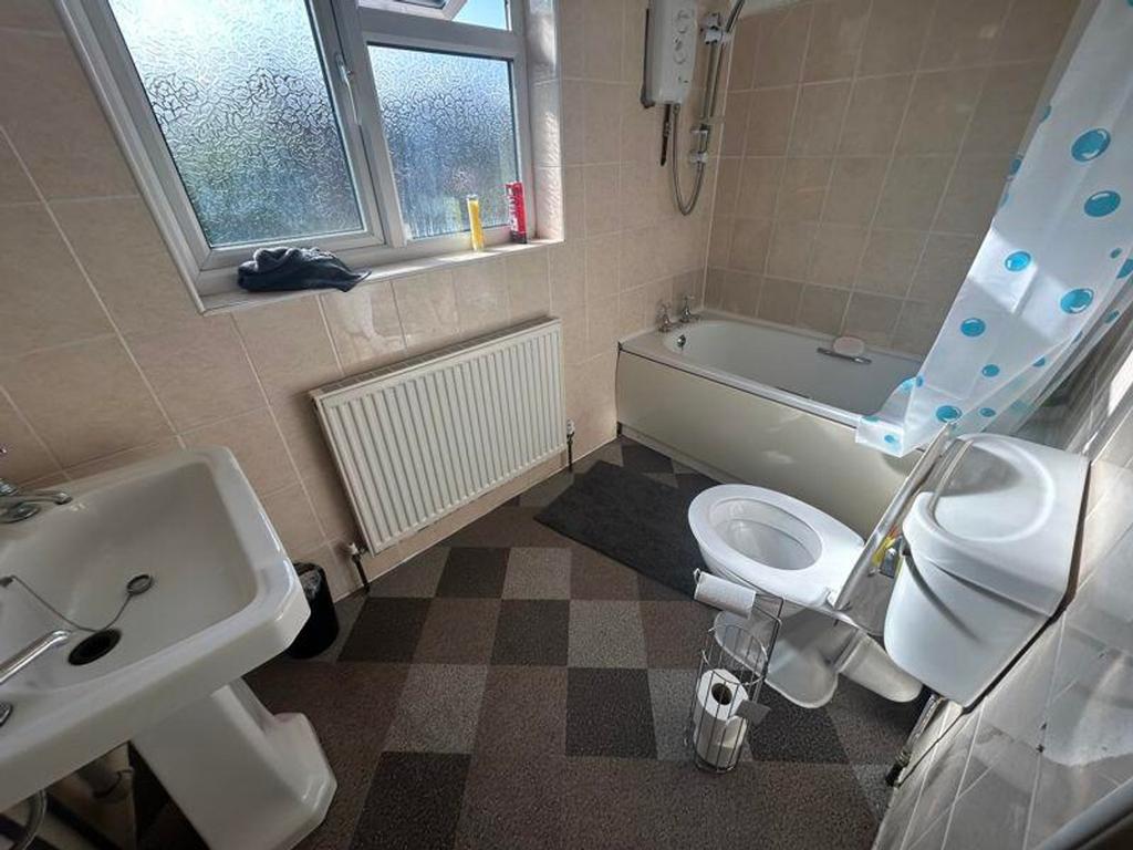 A bright and clean bathroom featuring a bathtub...