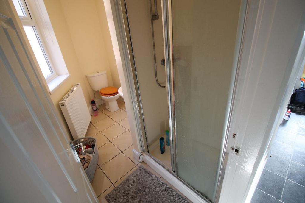 A well-lit bathroom featuring a spacious shower...