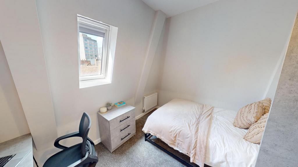 A bright and tidy double bedroom with a cozy at...