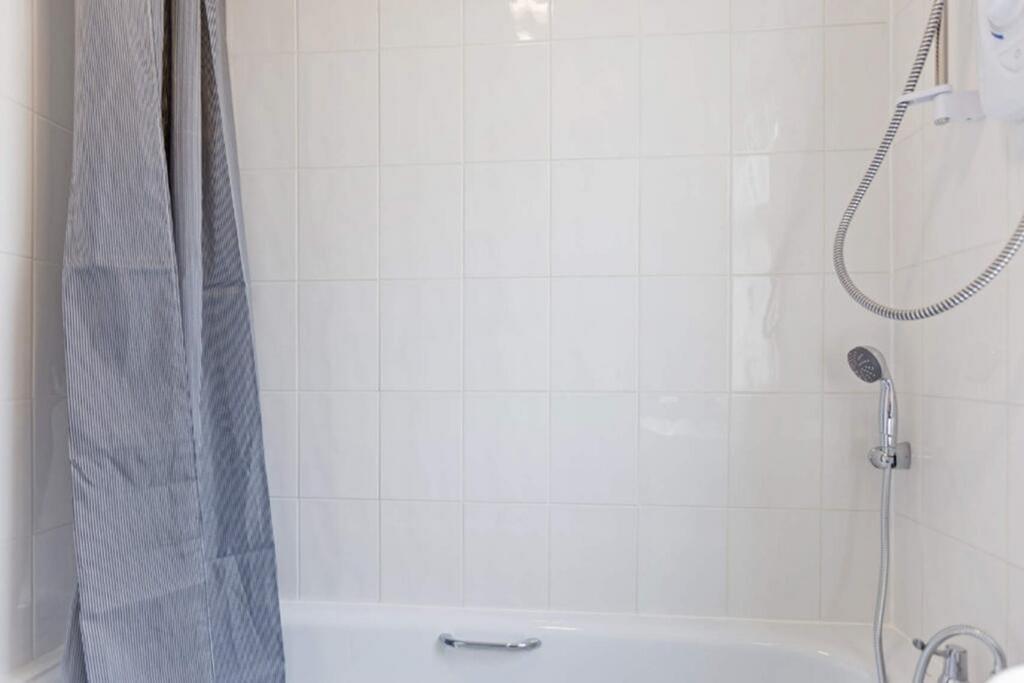 A bright and clean bathroom featuring a bathtub...