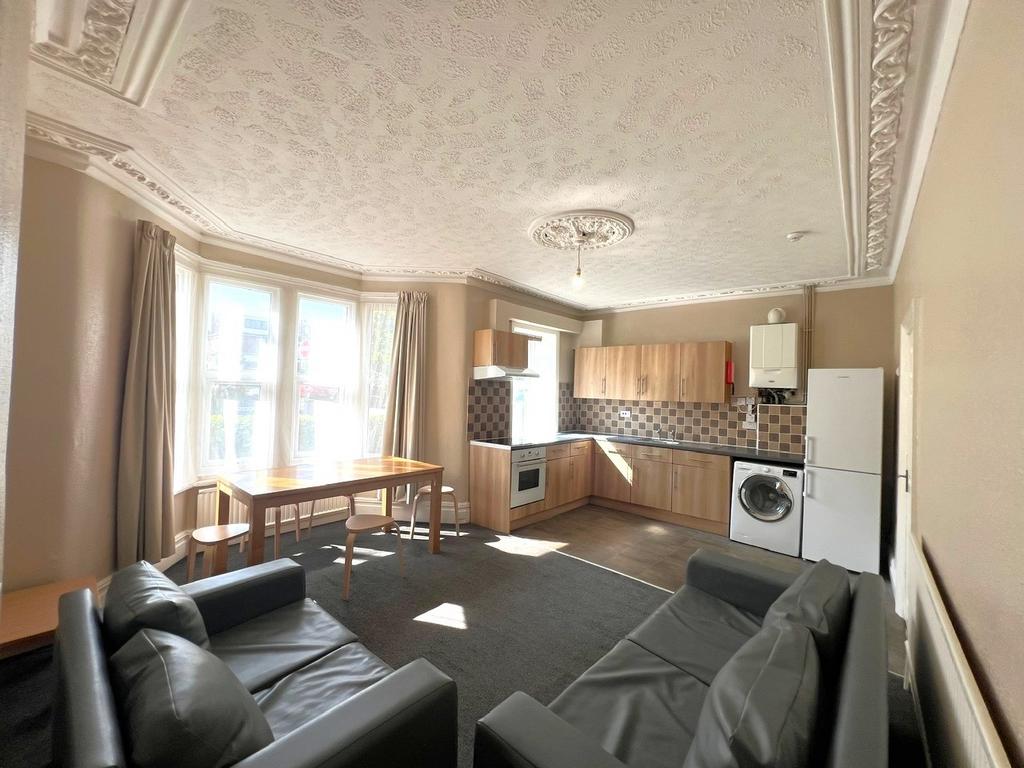 Bright open-plan living area with a bay window,...