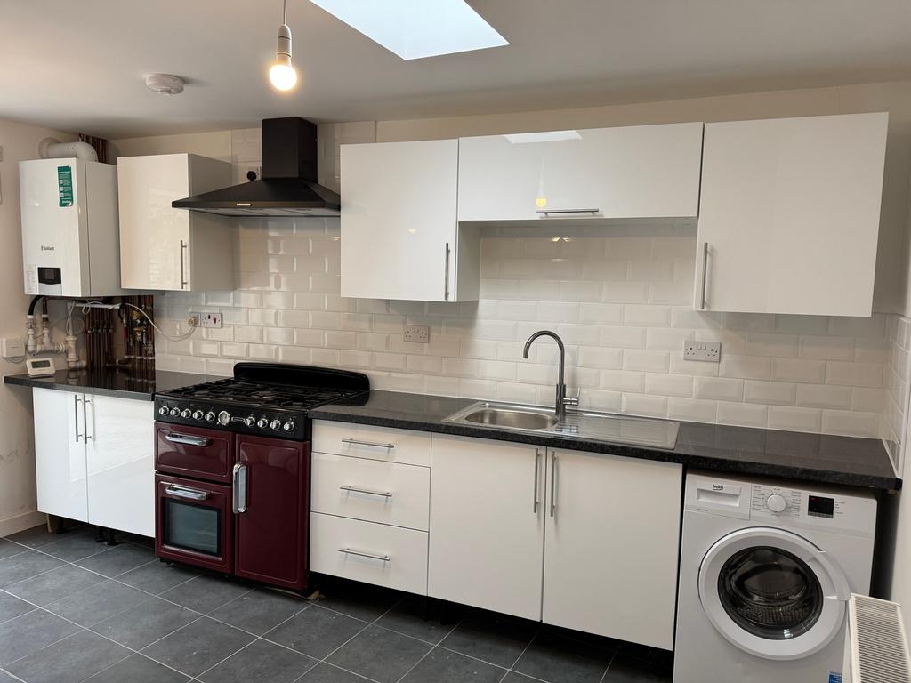 Modern kitchen featuring sleek white cabinetry,...