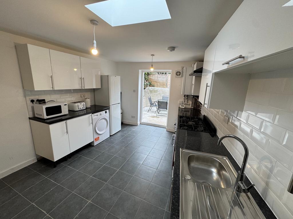 This modern kitchen features sleek white cabine...