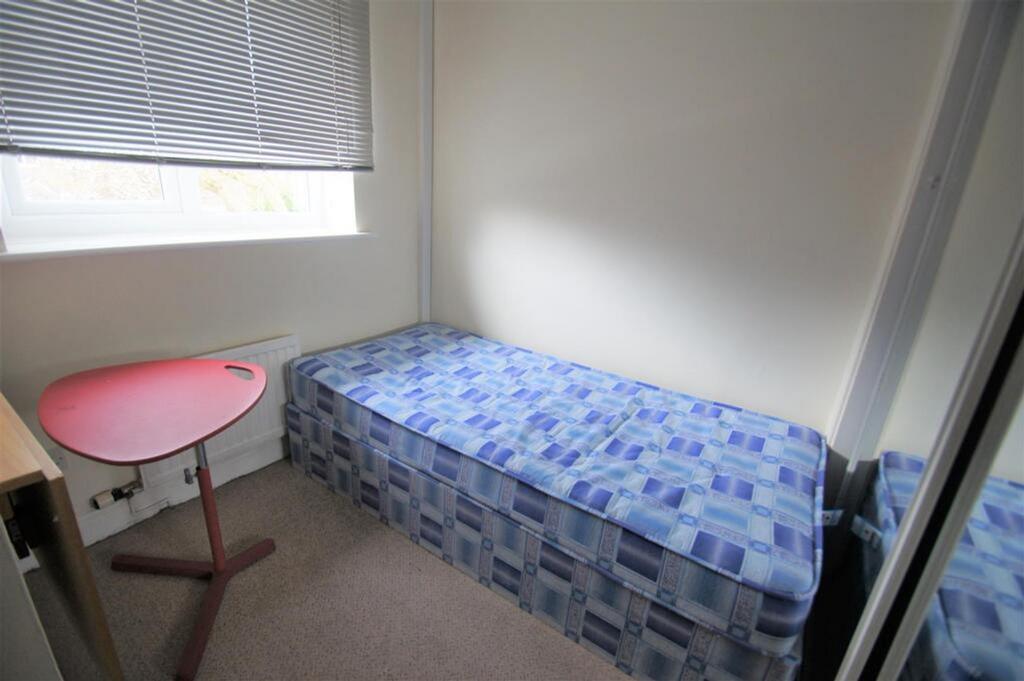 This cozy single bedroom features a comfortable...