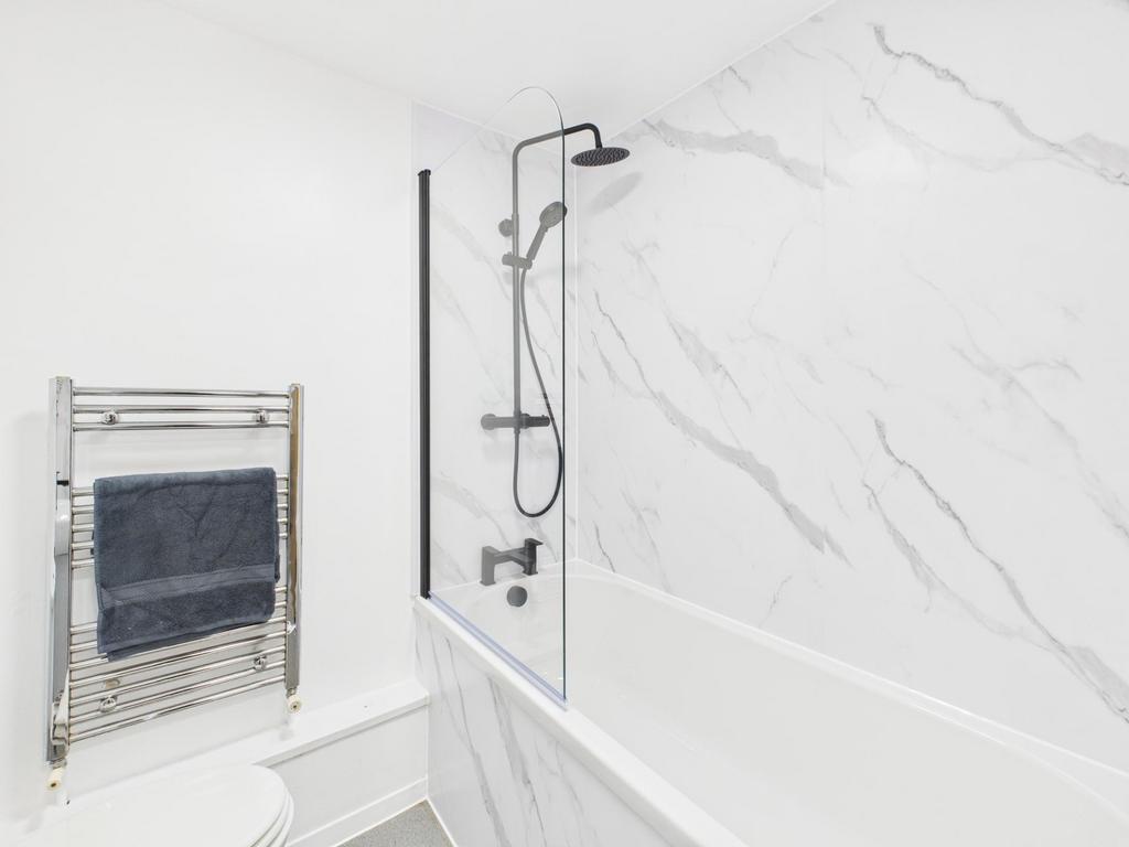 Bright, modern bathroom with a white bath and a...