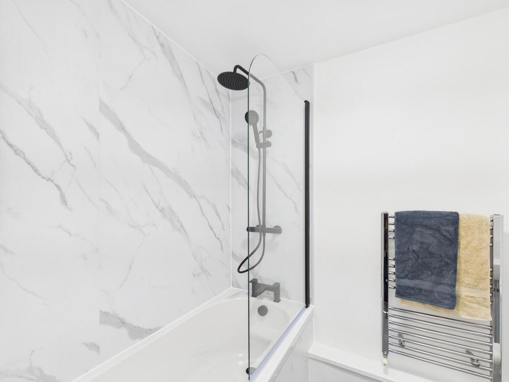 Bright, modern bathroom with a bathtub and over...