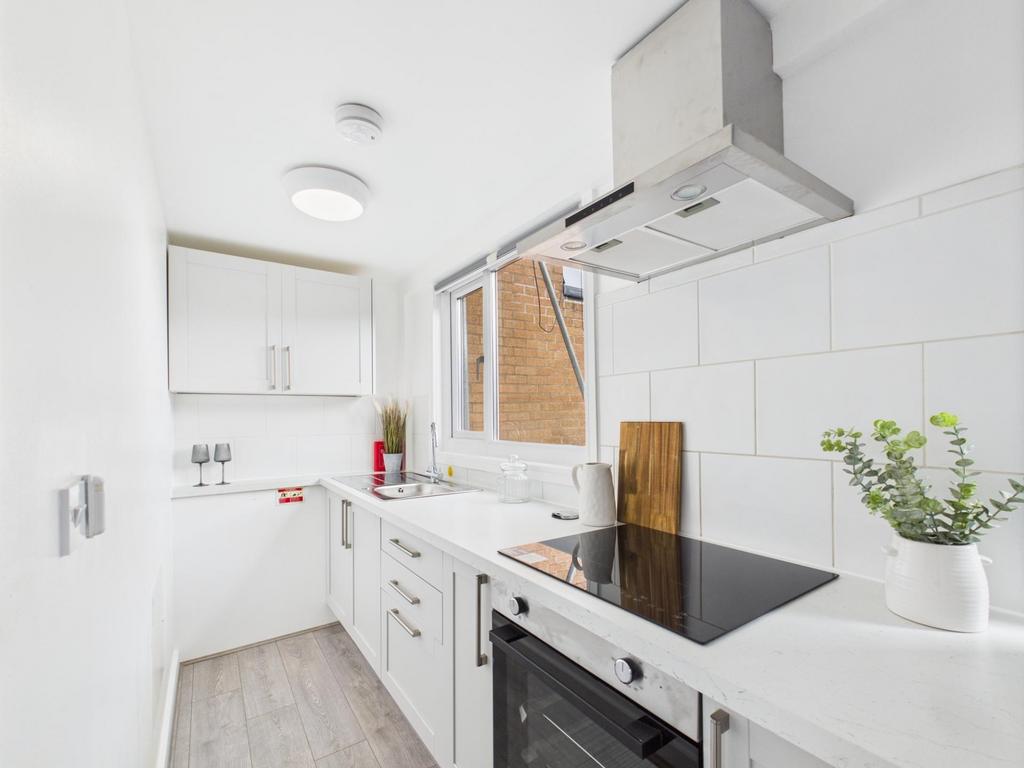 Bright, modern galley kitchen with white cabine...