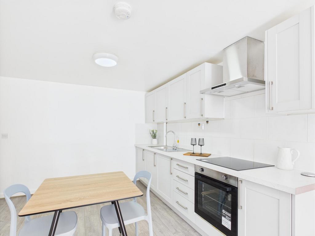 Bright, modern fitted kitchen with white cabine...