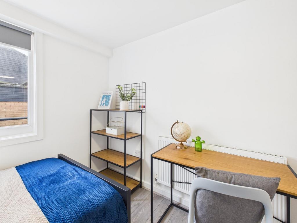 Bright, simply furnished bedroom with a desk fo...