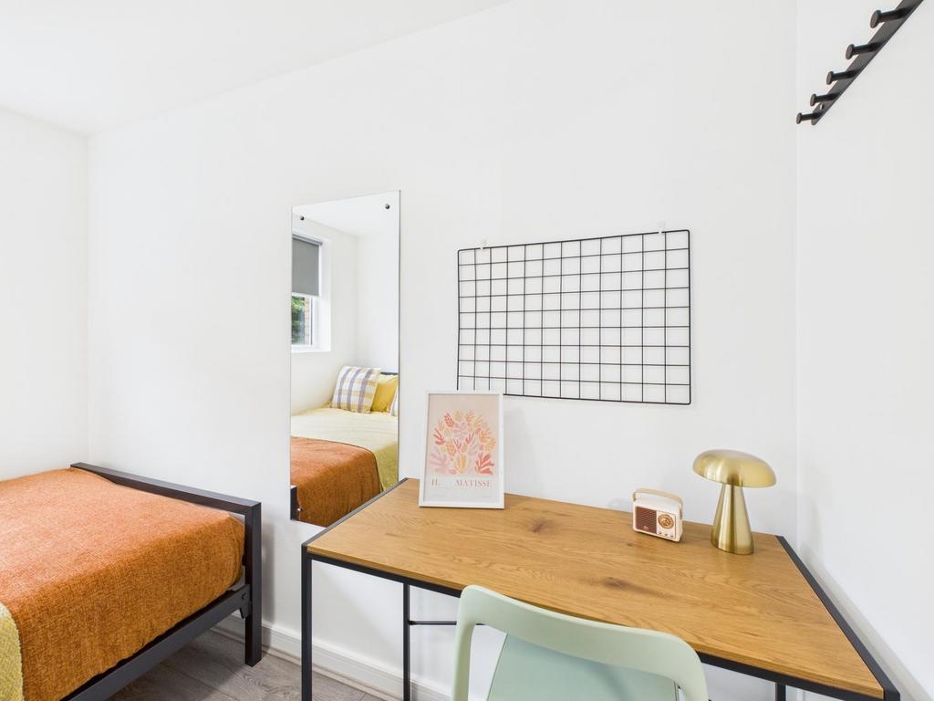 Bright, minimalist bedroom with a tidy study ar...