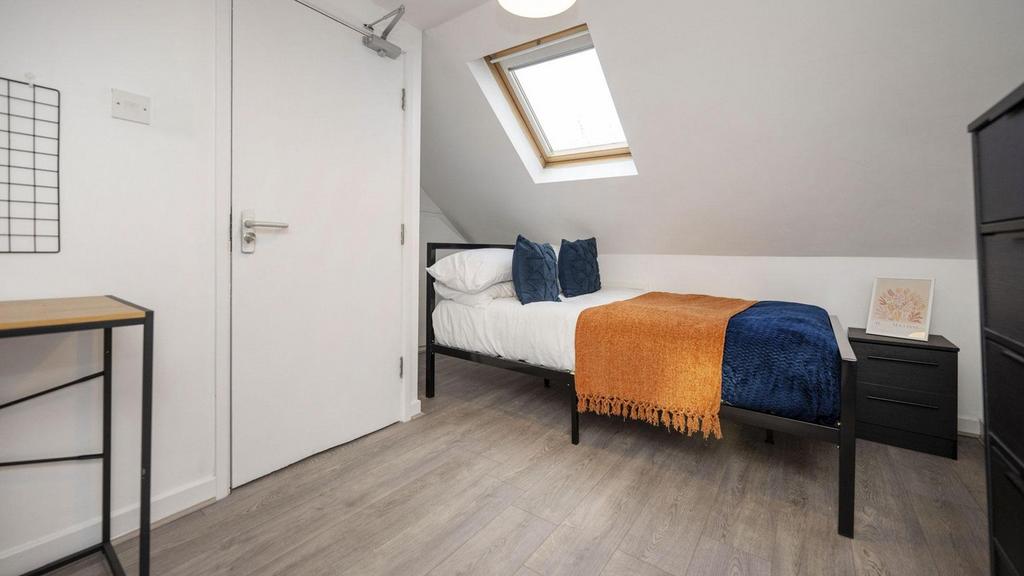 A bright and tidy single bedroom with modern de...