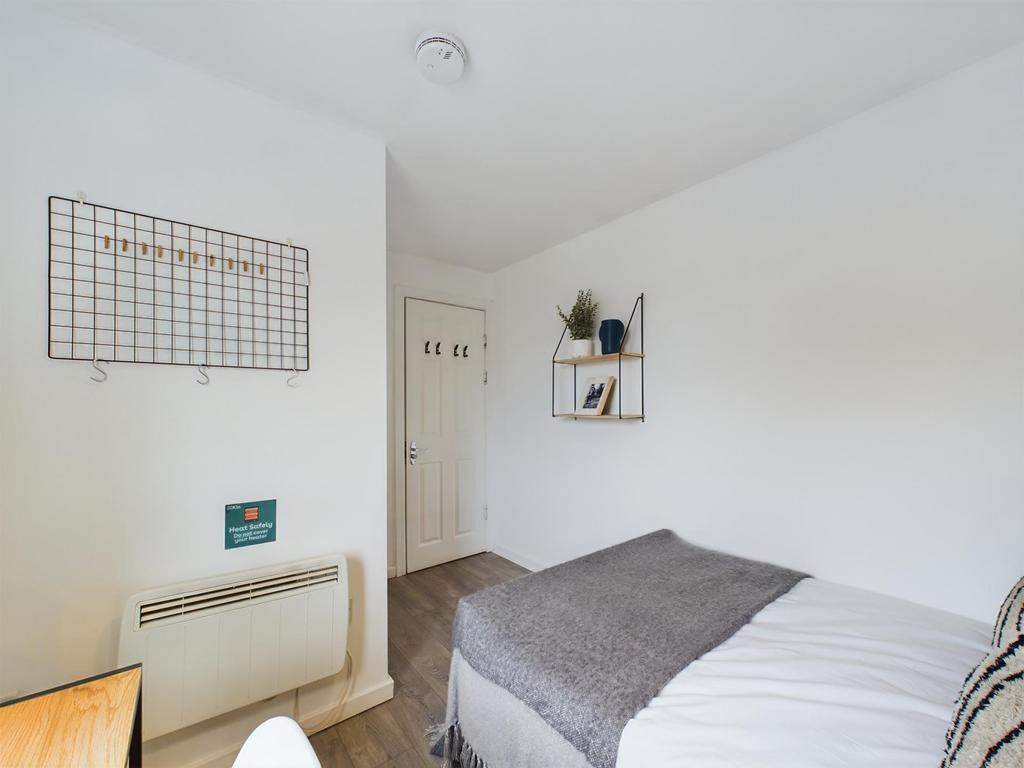 A neat, simply furnished bedroom with bright wh...