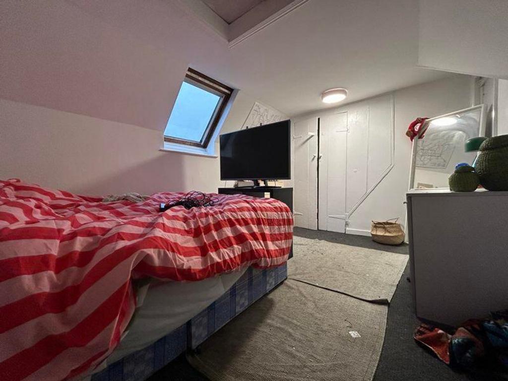 A cozy double bedroom with a modern TV setup an...