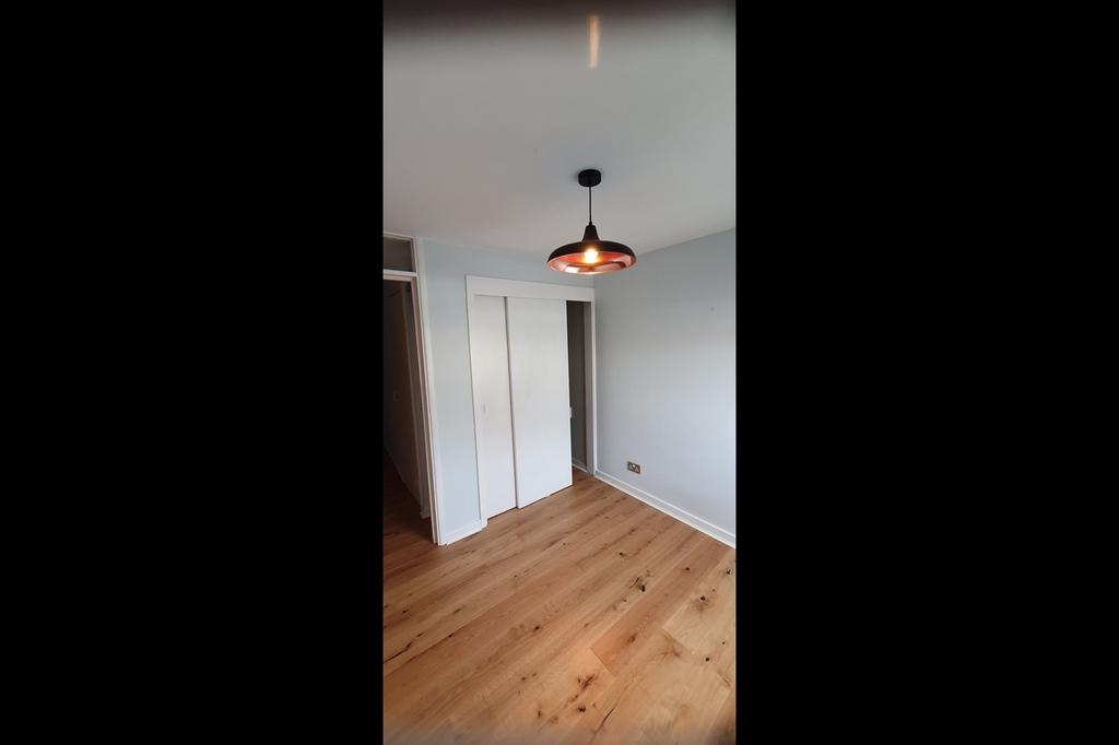 This inviting double bedroom features warm wood...
