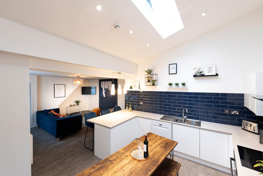 This modern kitchen features sleek white cabine...