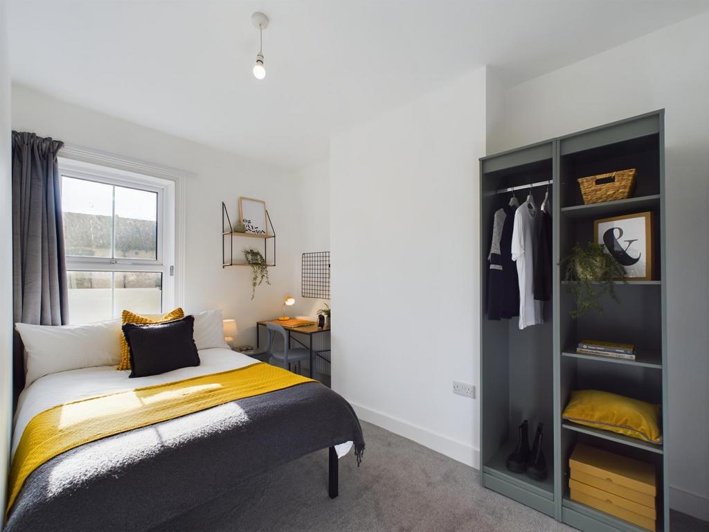 A modern, well-lit bedroom featuring a comforta...