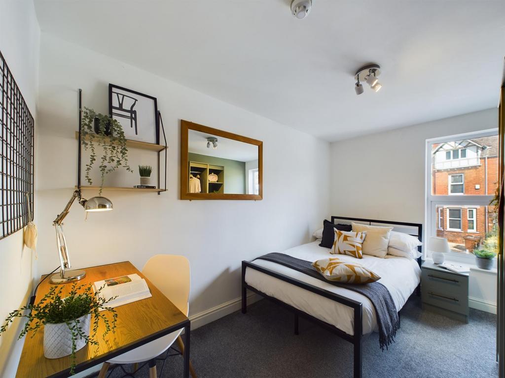 A bright and tidy small bedroom featuring a com...