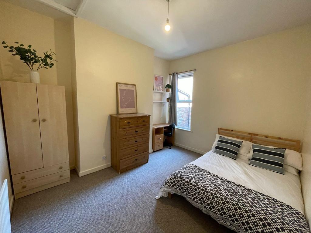 A bright and welcoming bedroom featuring a comf...
