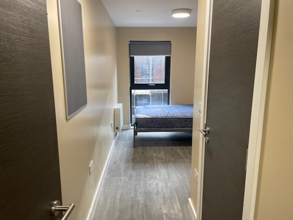 This well-lit single bedroom features a comfort...