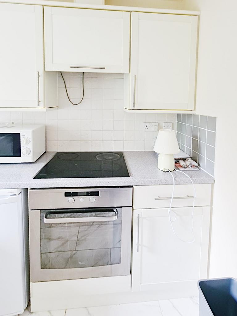 Bright compact modern kitchen with white cabine...