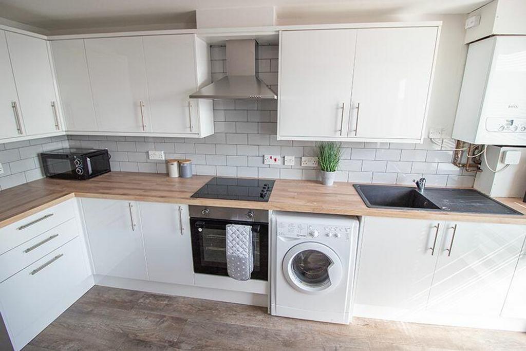This modern kitchen features sleek white cabine...