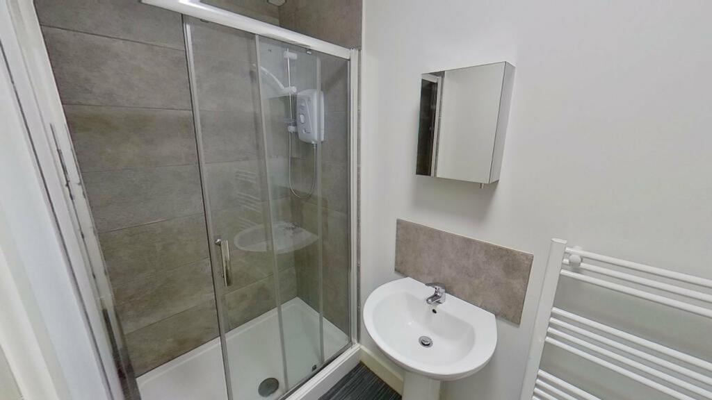 A modern bathroom featuring a sleek glass showe...