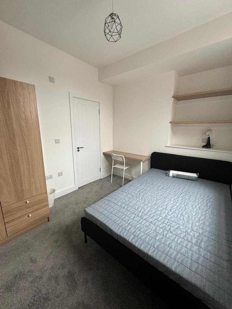 A spacious and tidy double bedroom featuring a ...
