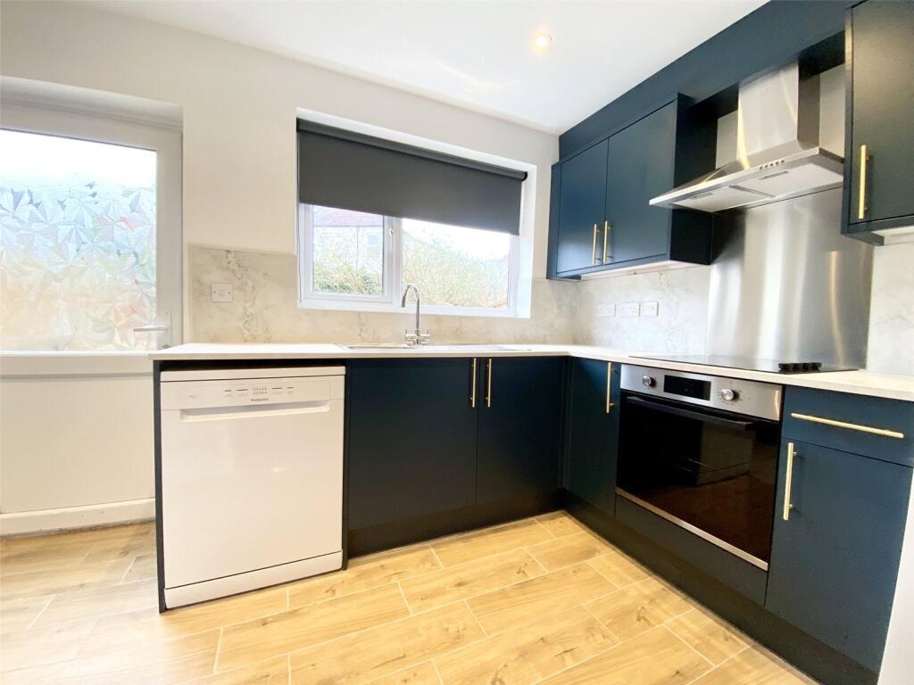 A modern kitchen featuring sleek navy cabinets,...