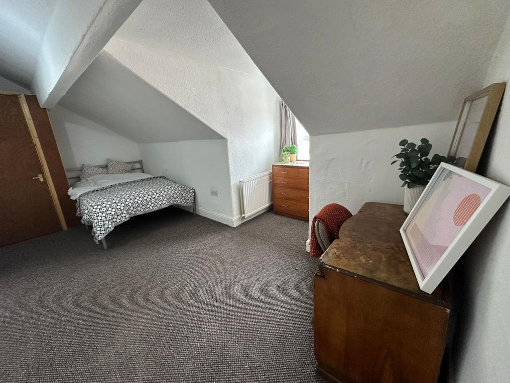 A cozy single bedroom with a sloped ceiling, fe...