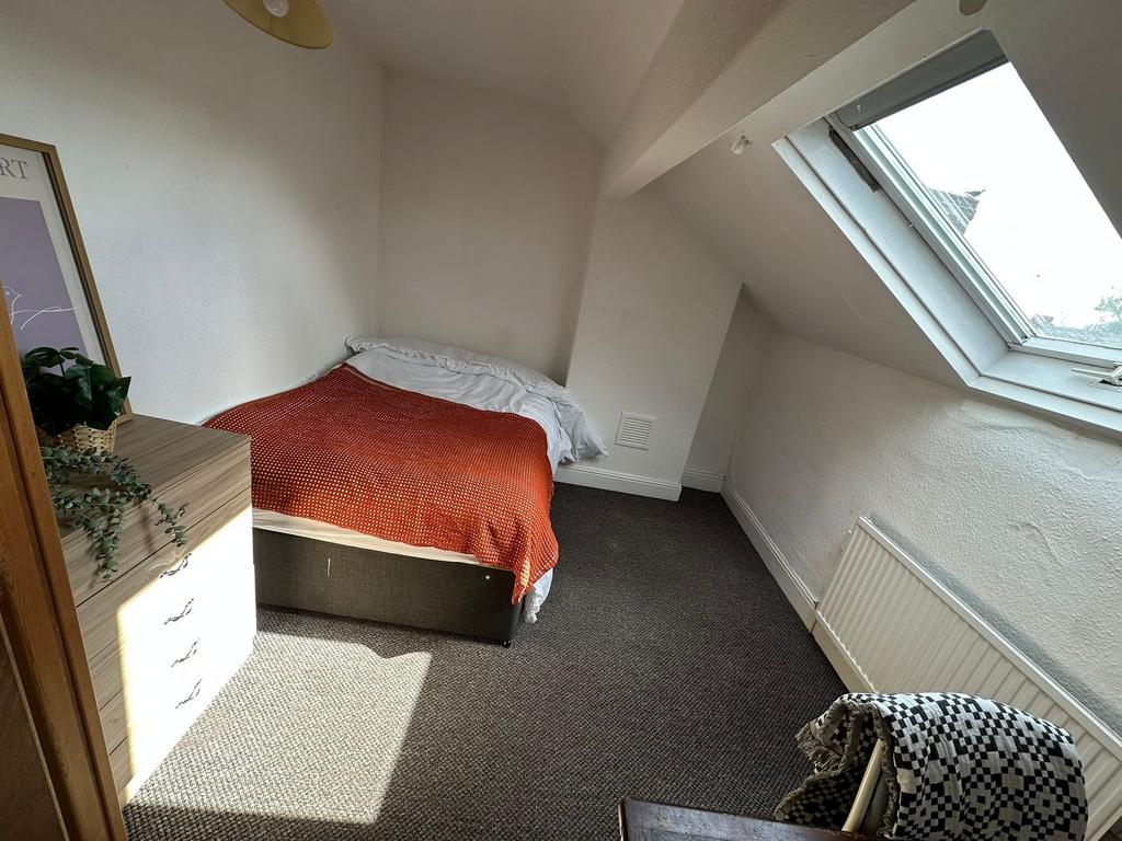 A cozy single bedroom featuring a small bed wit...