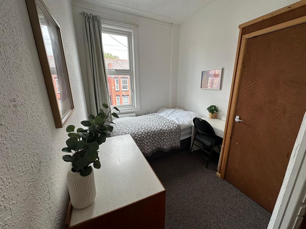 A small, tidy bedroom with a single bed positio...