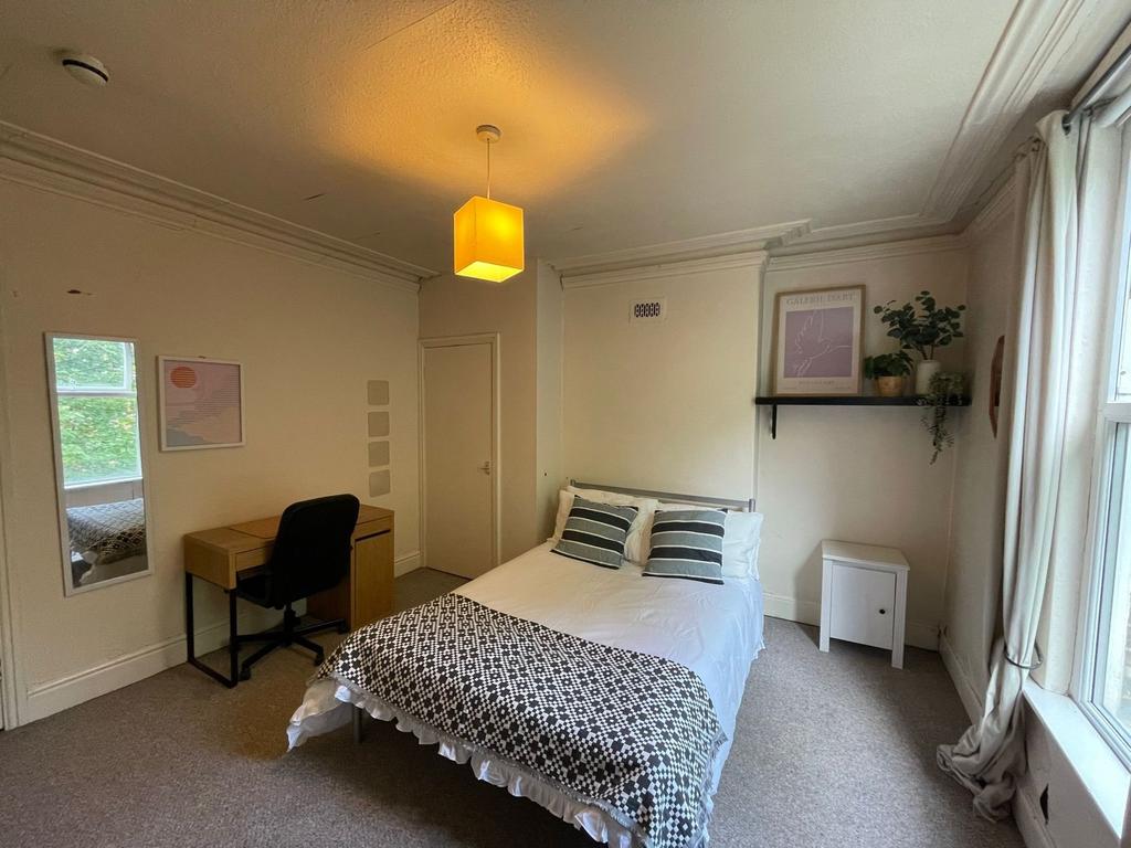 A well-lit, inviting bedroom featuring a large ...