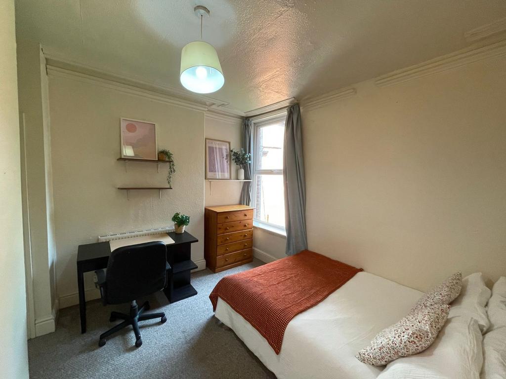 A bright and cozy bedroom featuring a comfortab...
