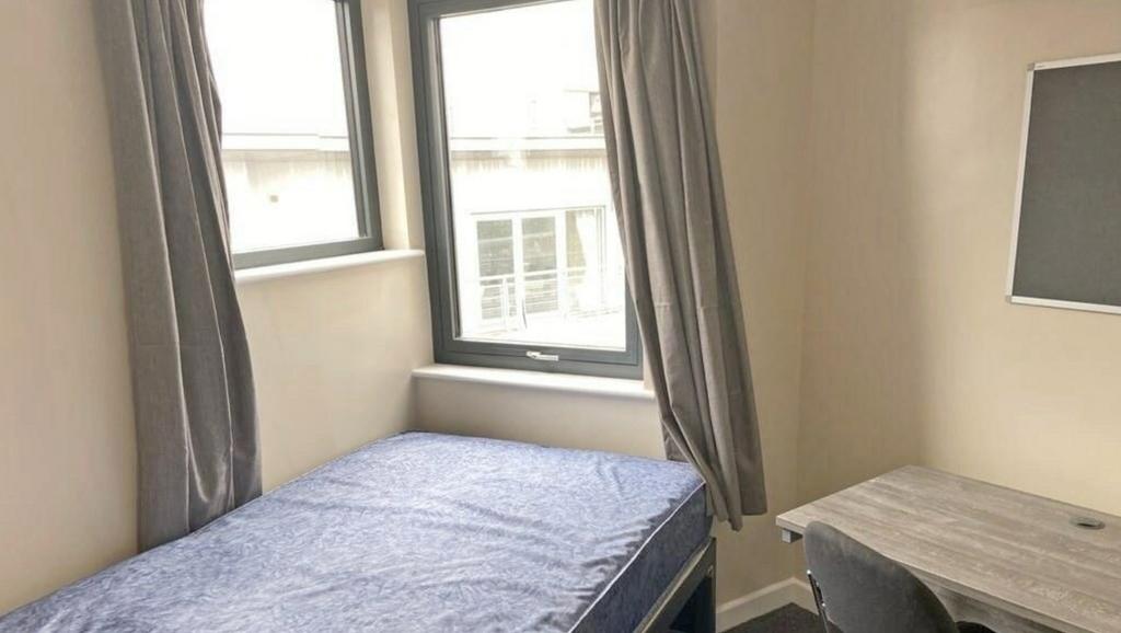 A bright and tidy single bedroom featuring larg...