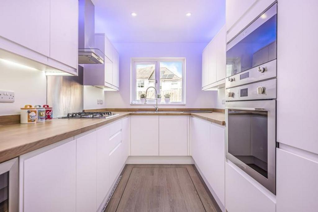 This modern kitchen features sleek white cabine...